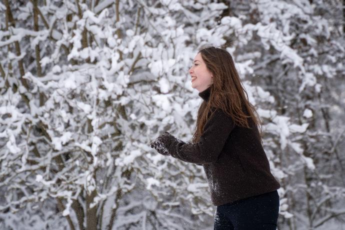 Model trägt dunkelbraune Fäustlinge und Rollkragenpullover im Schnee