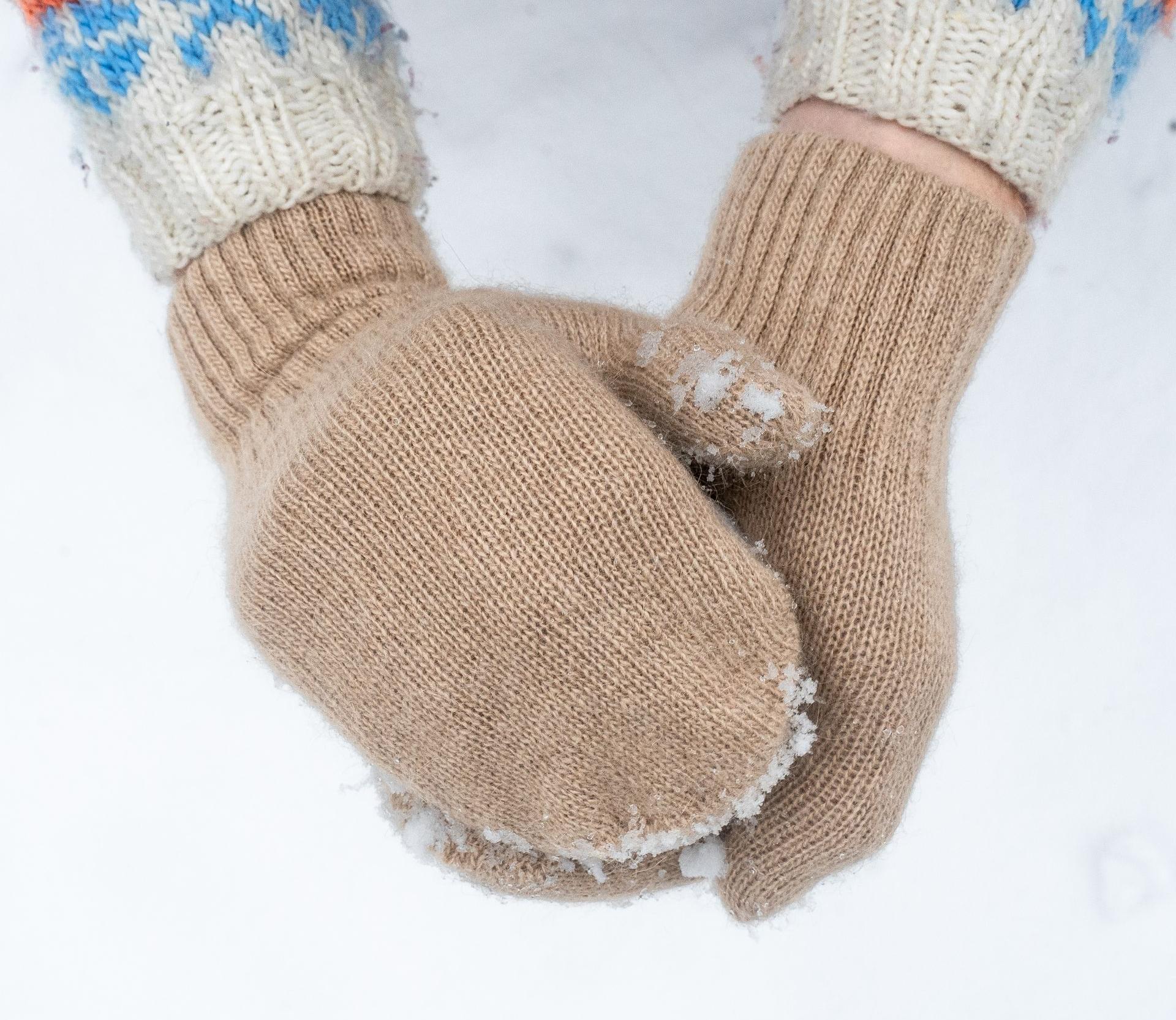 Detailfoto von Händen die beige Fäustlinge aus Kamelwolle tragen