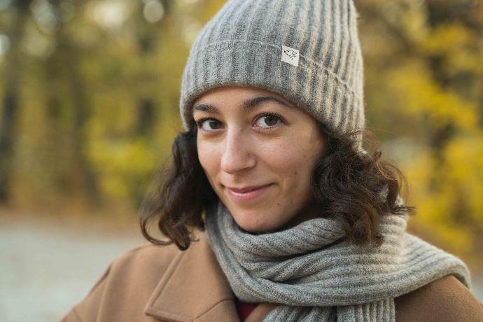 Model mit grauer Mütze und grauem Schal aus Yakwolle im Wald.