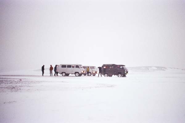 Cars and people standing in a white snowy backdrop