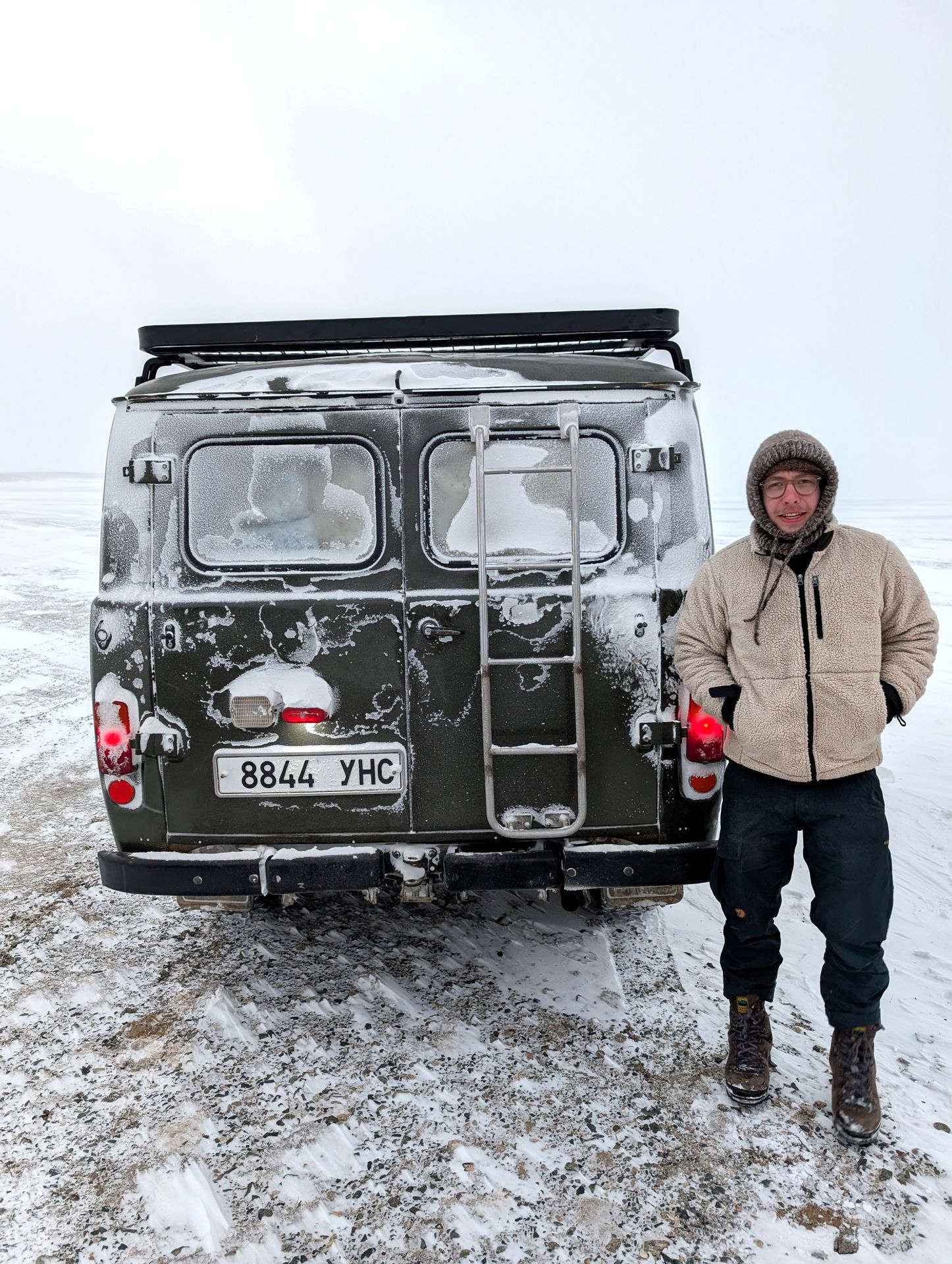 Man in woolen clothing in front of frozen car