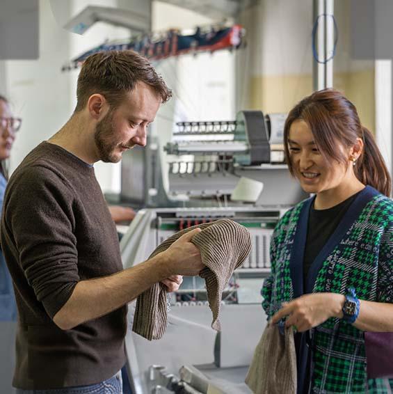 A man and a woman examine woollen products
