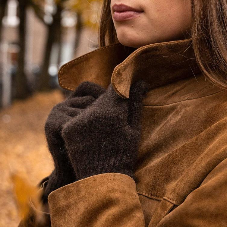 Dark brown gloves holding the collar of a brown jacket