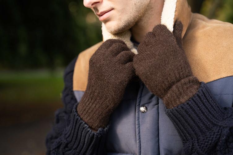 Mann hält seinen Kragen mit braunen Handschuhen