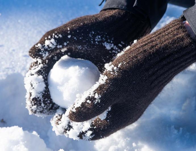 Fäustlinge aus Wolle halten Schneeball