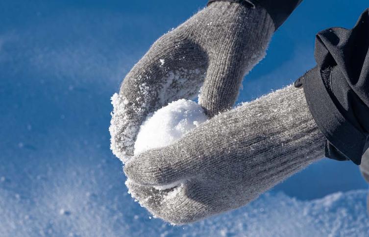 Grey mittens hold snowball