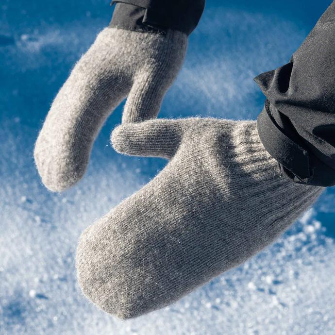 Two mittens are stretched out in front of a blue background