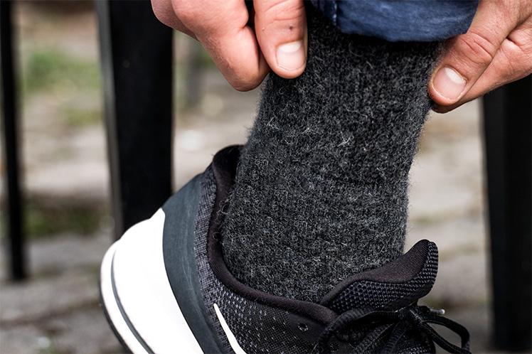 Dunkle Wollsocken werden in Schuhen angezogen